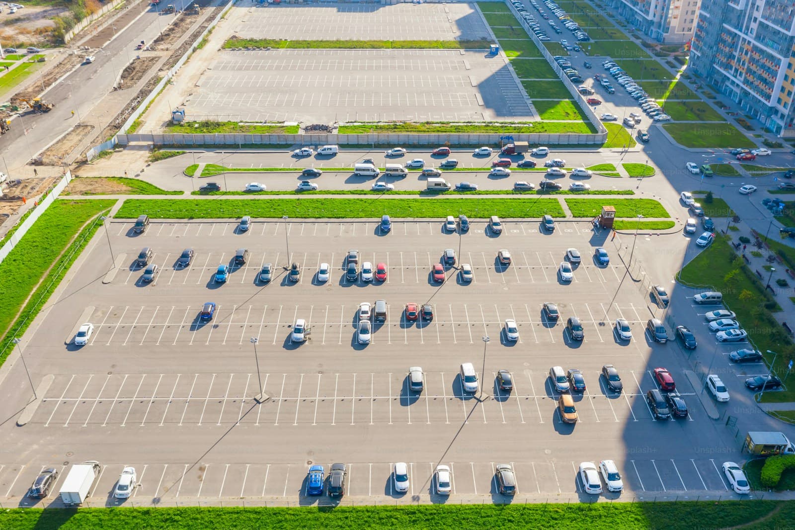 Aerial view of large parking lot with cars and surrounding buildings